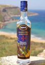 A bottle of Maltese carob liqueur with the north coast of Gozo Island in the background